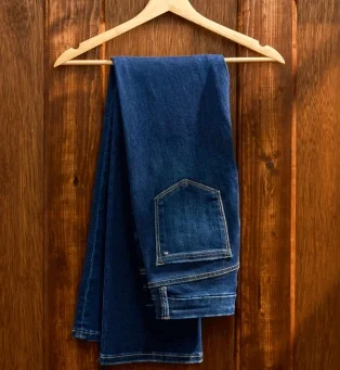 Stack of folded jeans in assorted blue and green washes.