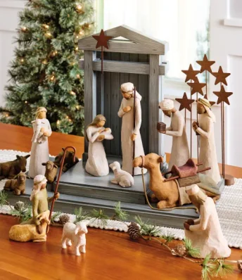 Image of a nativity scene displayed on a side table in front of a lit up Christmas tree