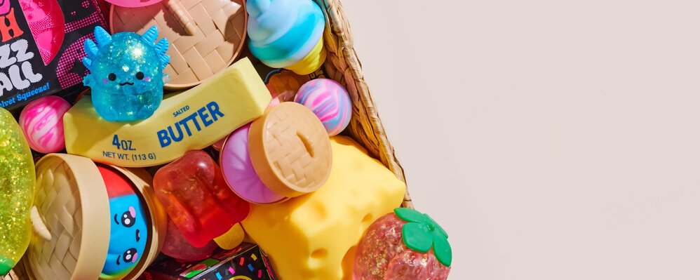 Basket overflowing with colorful squishies and sensory toys on a light neutral background.