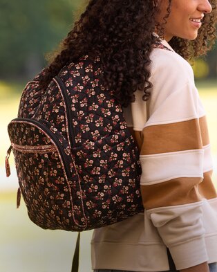 Person wearing a floral Vera Bradley backpack over a colorblock sweatshirt outdoors.