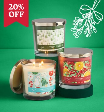 Three candles displayed next to Christmas tree ornaments in front of a green background