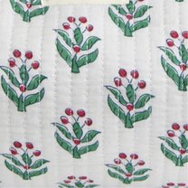 Close-up of white quilted fabric with a green and red holly-inspired print.