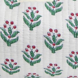 Close-up of white quilted fabric with a green and red holly-inspired print.