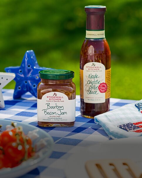 Summer Stonewall Kitchen condiments and gourmet pantry items displayed on a picnic blanket with patriotic décor.