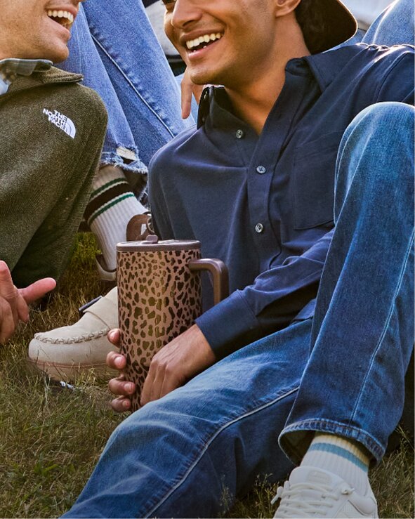 Students relaxing outdoors with a reusable tumbler. Shop hydration essentials.