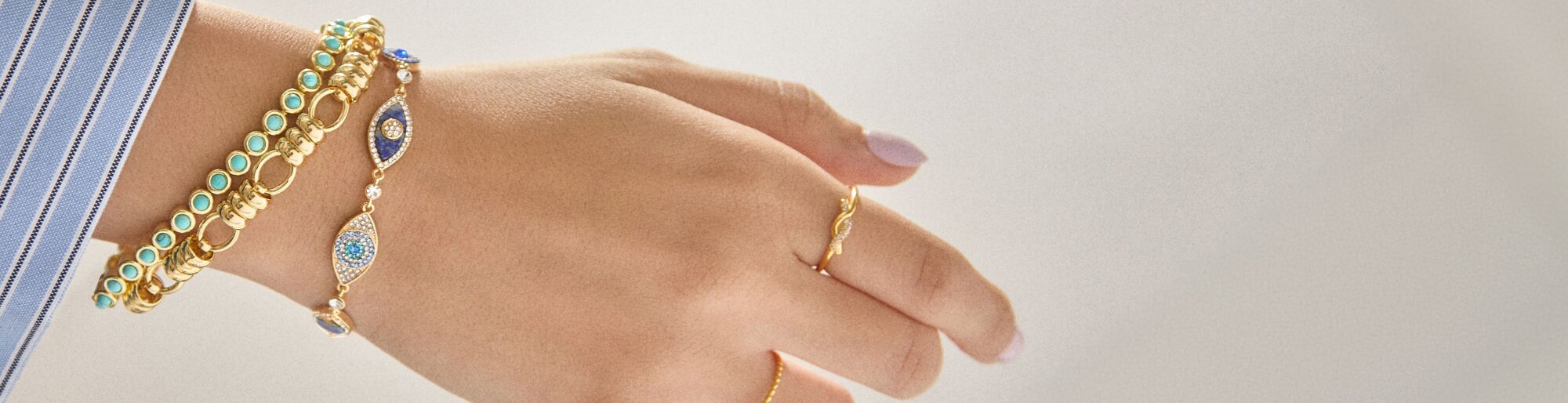 Close up of a woman's wrist and hand wearing BaubleBar rings and bracelets
