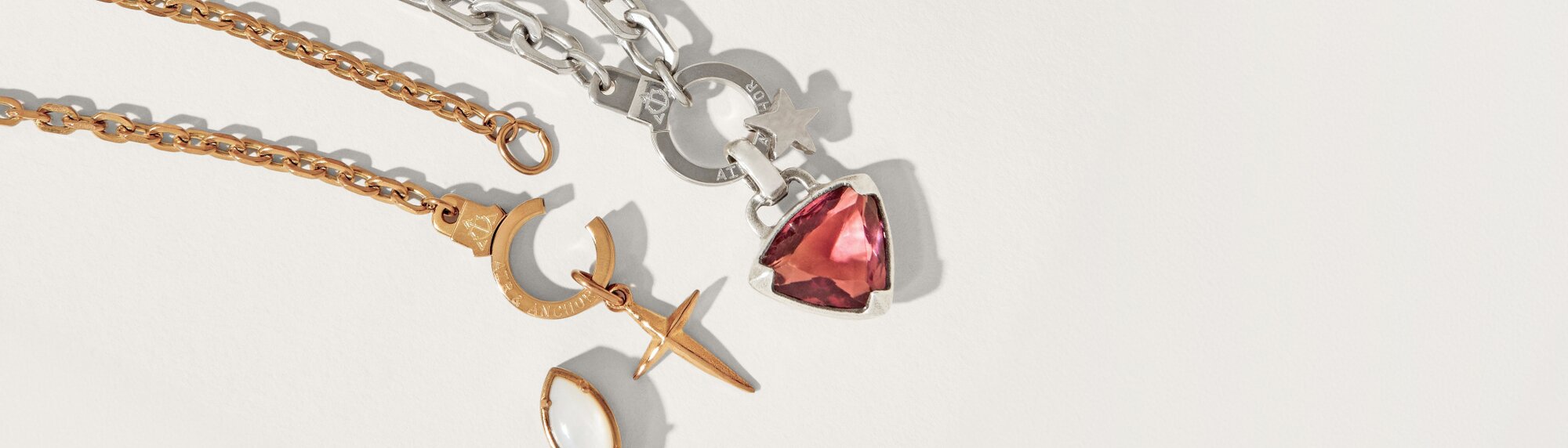 Image of Air & Anchor Cuff Keeper chains. Silver Chain has a red crystal charm and a silver star charm, gold chain has a gold cross charm.