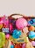 Basket overflowing with colorful squishies and sensory toys on a light neutral background.