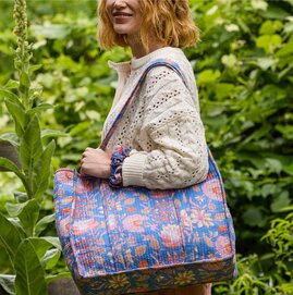 Woman outdoors carrying a blue floral quilted tote bag with a matching scrunchie.