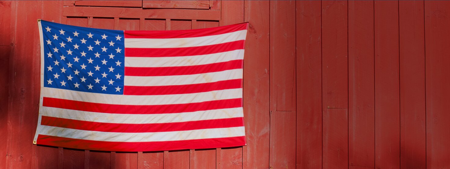 An american flag on the side of a red barn