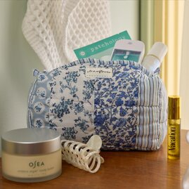 Blue-and-white patchwork quilted cosmetic bag filled with beauty essentials, displayed with skincare and hair accessories.