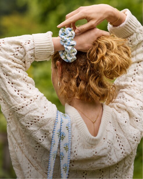 Woman wearing a cream knit sweater and a colorful Strawflower scrunchie.