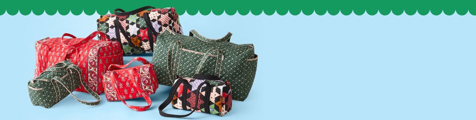 Various Vera Bradley duffels, cosmetic cases and ornaments in front of a Christmas  tree