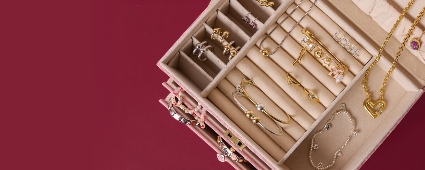 image of an open jewelry box on a maroon backgroung. features Cape Cod Jewelry, Italian charm bracelets and Kendra Scott.