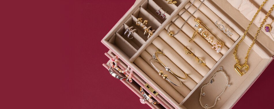 image of an open jewelry box on a maroon backgroung. features Cape Cod Jewelry, Italian charm bracelets and Kendra Scott.