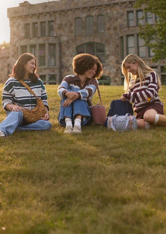 Three women sitting outdoors with Vera Bradley bags. Save 25% on Vera Bradley totes, bags and crossbodies, in-store and online.