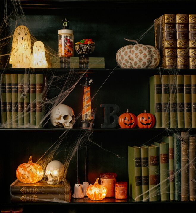 Halloween display with glowing pumpkins, ghosts, skulls, cobwebs and vintage books.