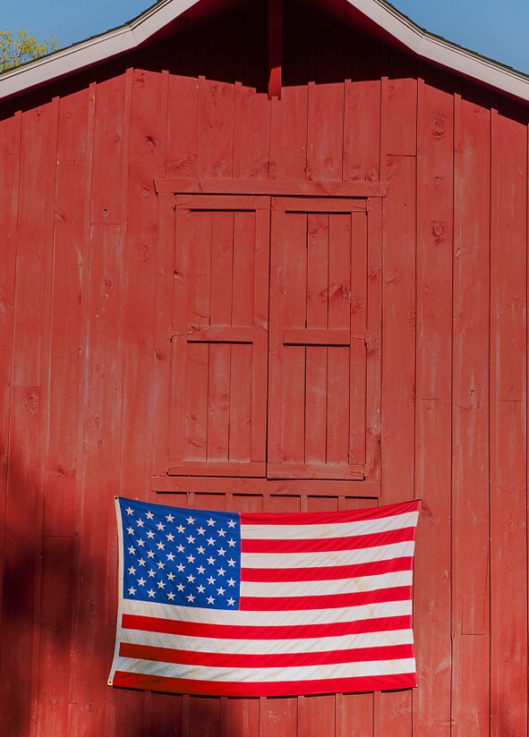An american flag on the side of a red barn