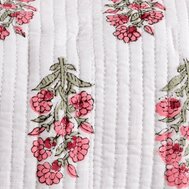 Close up of a white background with vertical stitched lines, decorated with small clusters of pink flowers and green leaves arranged in a repeating pattern.