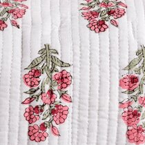 Close up of a white background with vertical stitched lines, decorated with small clusters of pink flowers and green leaves arranged in a repeating pattern.