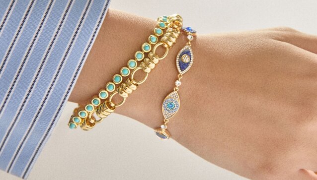 Close up of a woman's wrist and hand wearing BaubleBar rings and bracelets