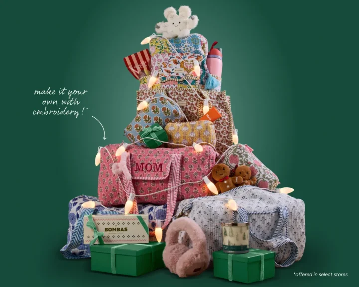 Image of quilted Strawflower duffel bags, tote bags, and cosmetic pouches stacked and displayed like a Christmas tree with Christmas lights. Text on the image reads "make it your own with embroidery" 