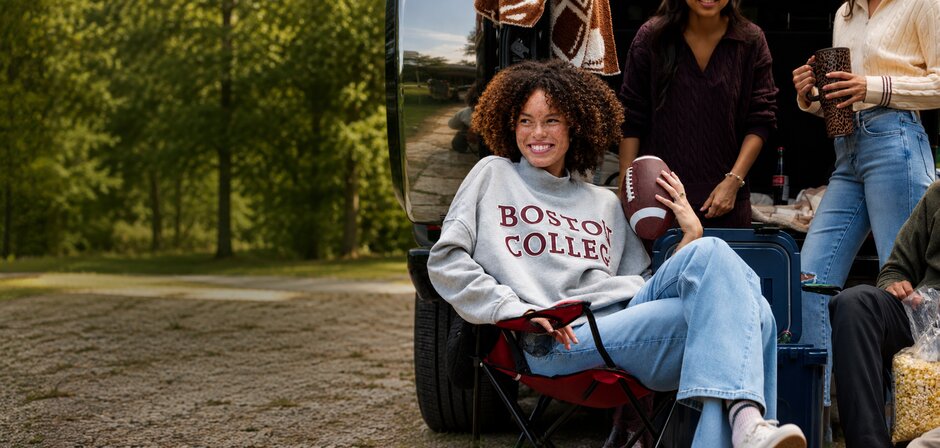 Friends gather at the back of an SUV with luggage and campus essentials, wearing cozy collegiate apparel for back-to-school season.