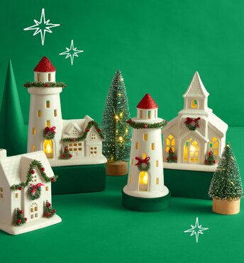 Festive holiday decor houses lit up in front of a green background