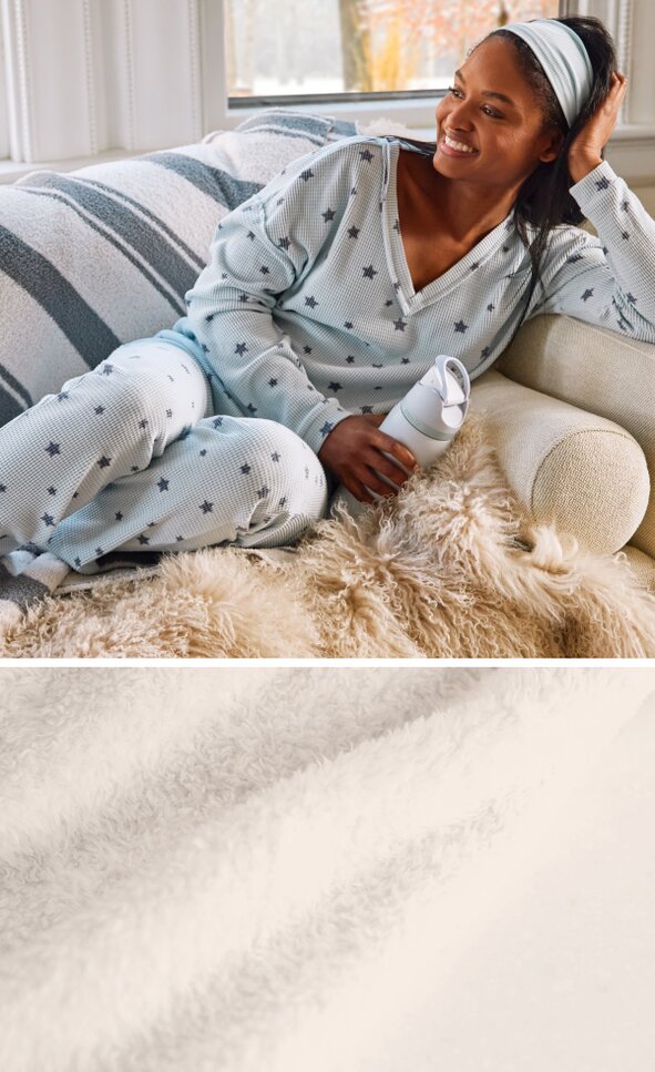 Model lounging on the couch wearing set of pajamas with star motif and fuzzy socks, holding an Owala water bottle