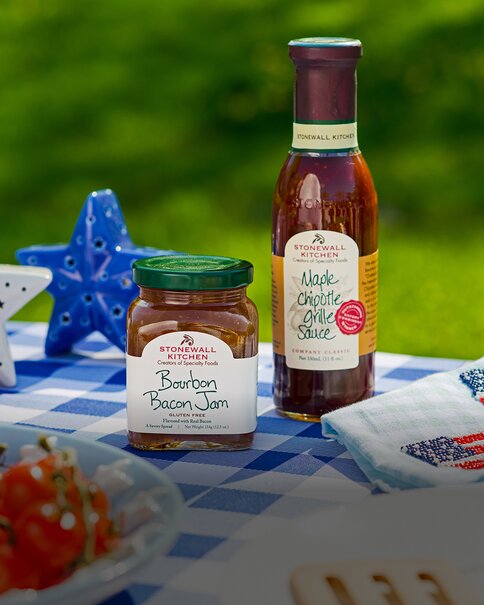 Summer Stonewall Kitchen condiments and gourmet pantry items displayed on a picnic blanket with patriotic décor.