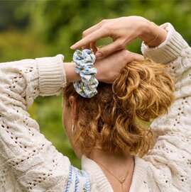 Woman securing her hair with a colorful floral scrunchie.