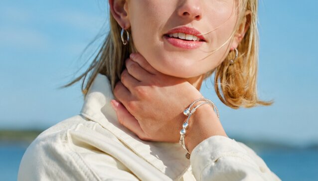 Woman wearing Cape Cod Jewelry bracelets and earrings by the water.