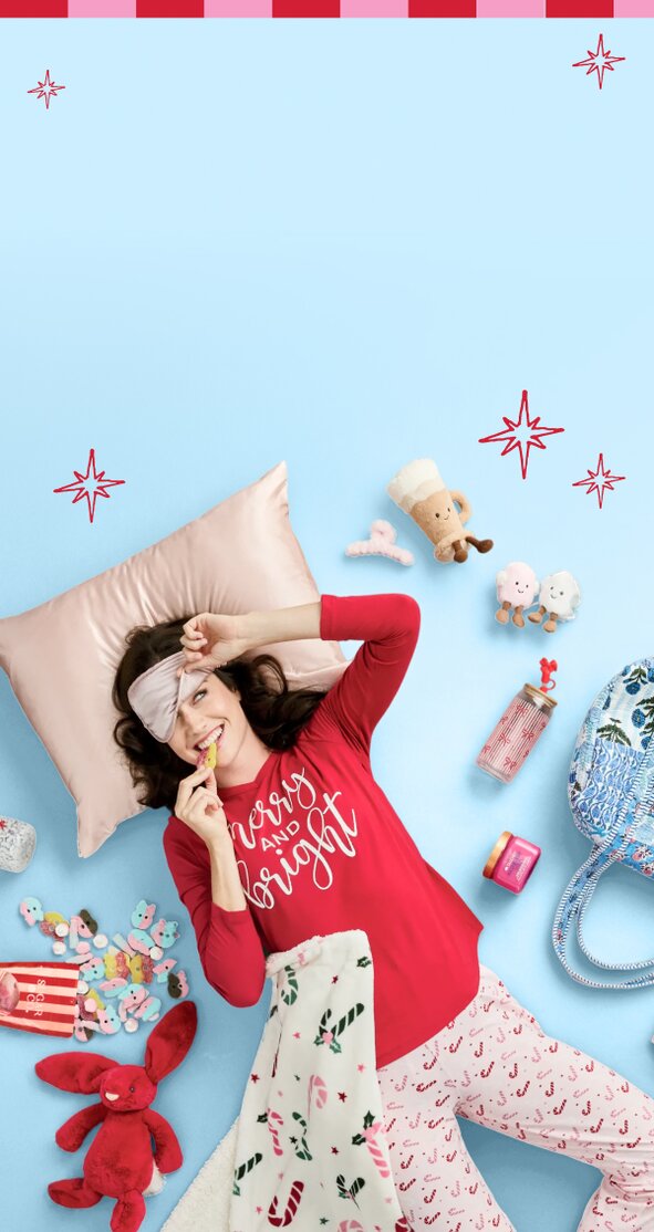 Two models wearing festive sweaters in the snow on a red background