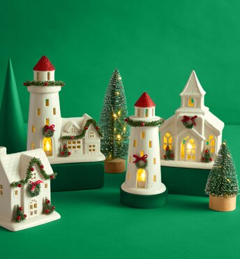 Festive holiday decor houses lit up in front of a green background