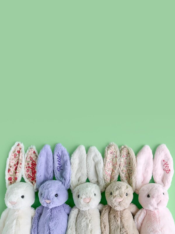 image of five jellycat bunnies in various colors. one with embroidered "Reese" on the ear and one with embroidered "Meg" on the ear