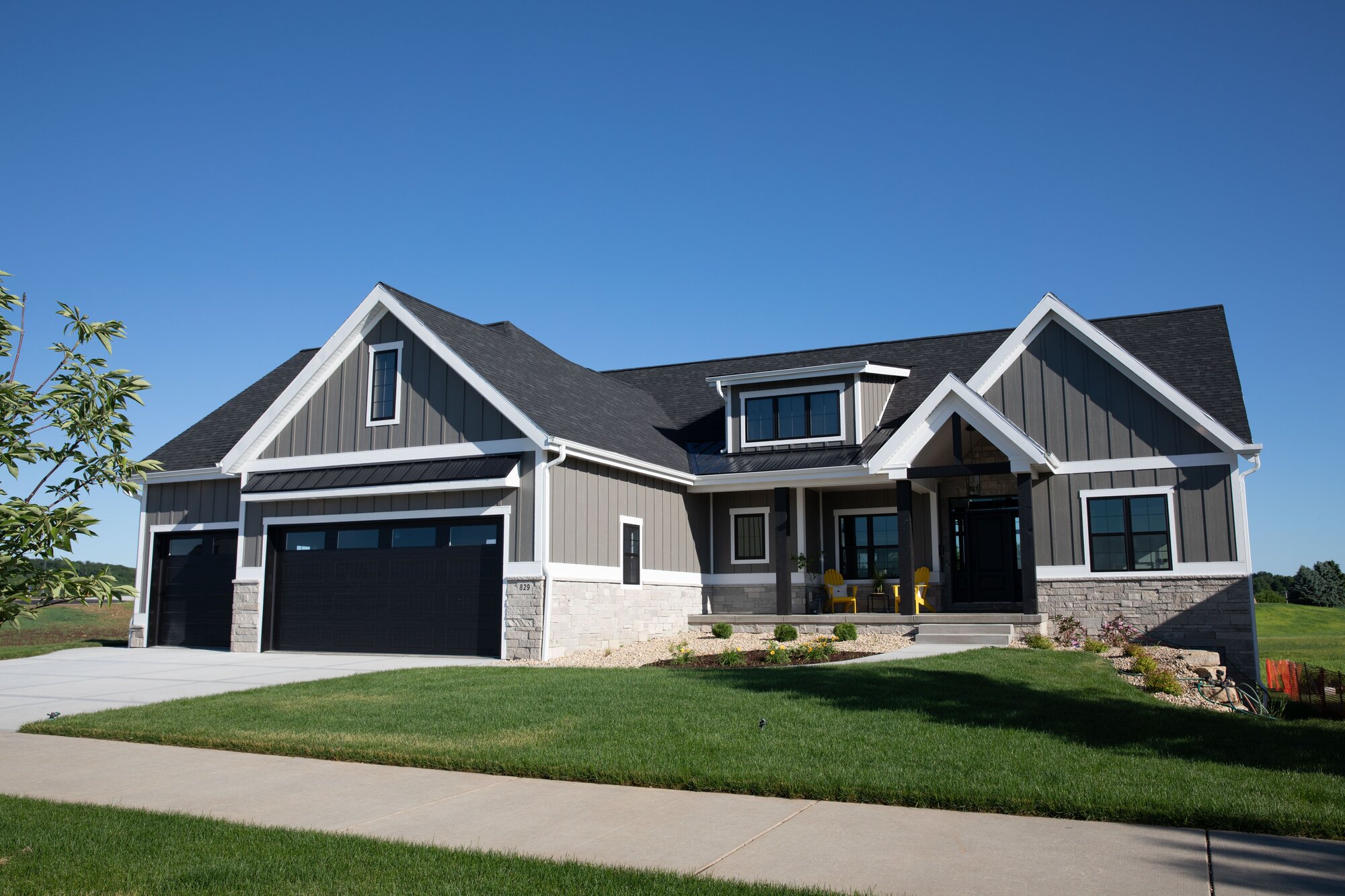 Gray craftsman home with attached garage and stone accents