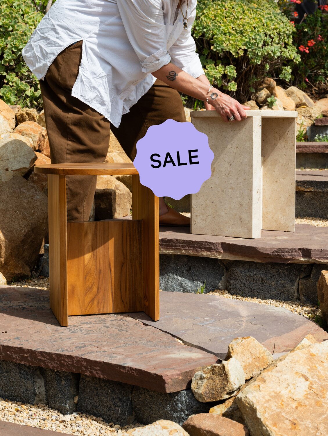 Person arranging stools in an outdoor setting.