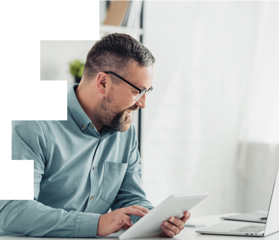Man in glasses smiling at his tablet because the mobile app is so great.