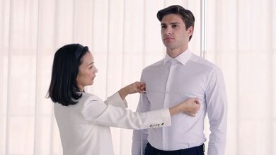 A woman measures a man's chest using a measuring tape.