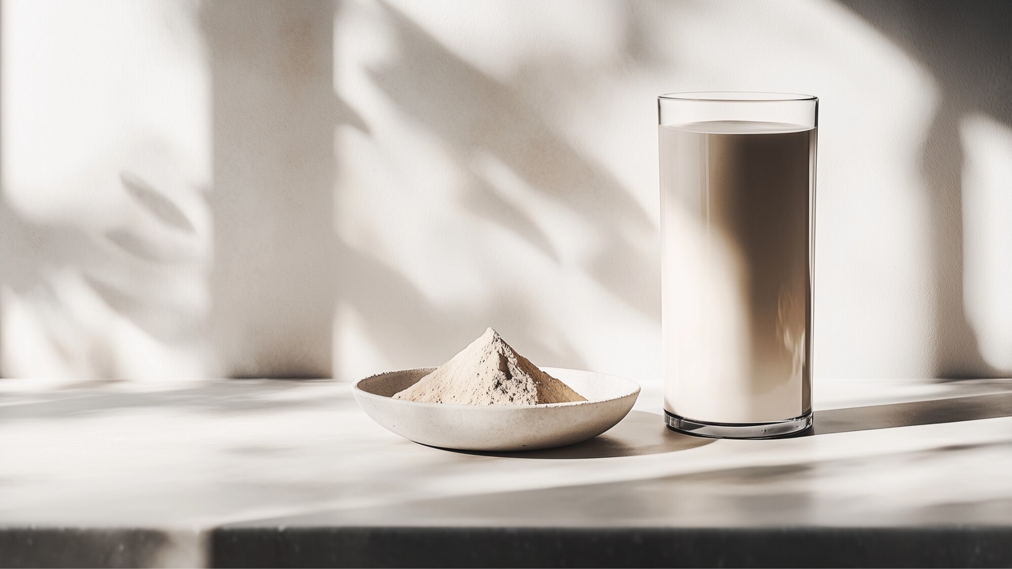 A glass of shake and a bowl of protein powder, highlighting the differences in meal replacement shakes vs protein shakes