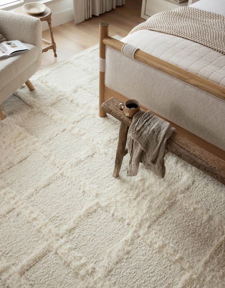 Beige, geometric shag rug underneath upholstered bed