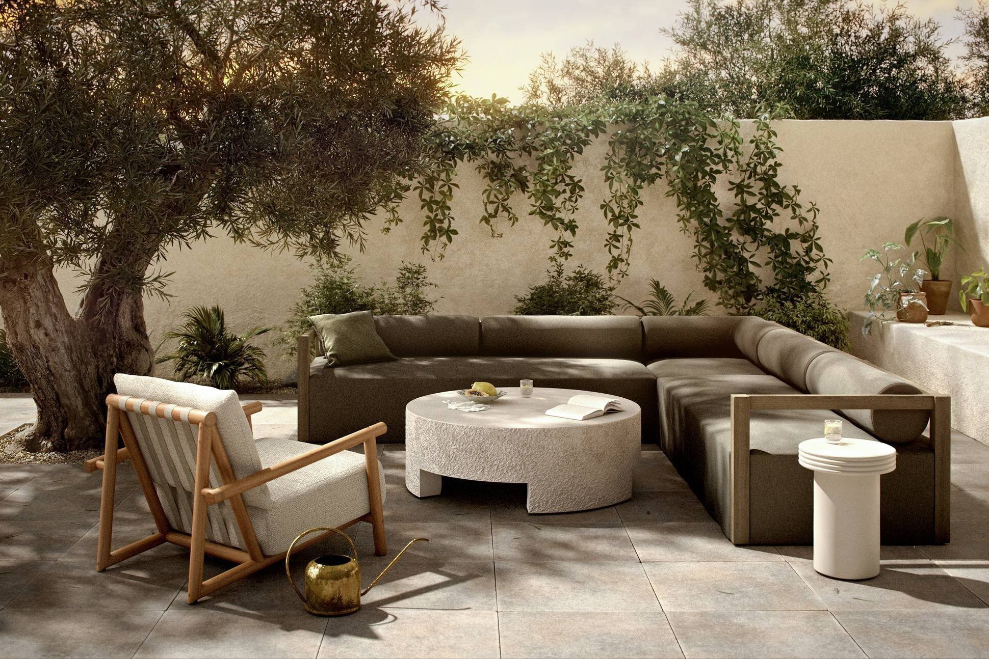 Sustainable outdoor upholstered sofa and armchair paired with stone coffee table arranged on a patio surrounded by trees.