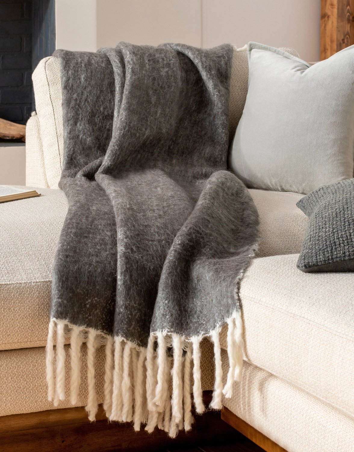 Gray throw with beige tassels drapped over a beige sectional