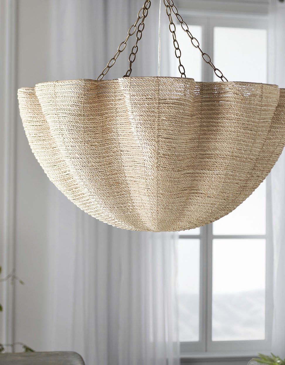 Pendant made of natural abaca hanging in front of window with white curtains