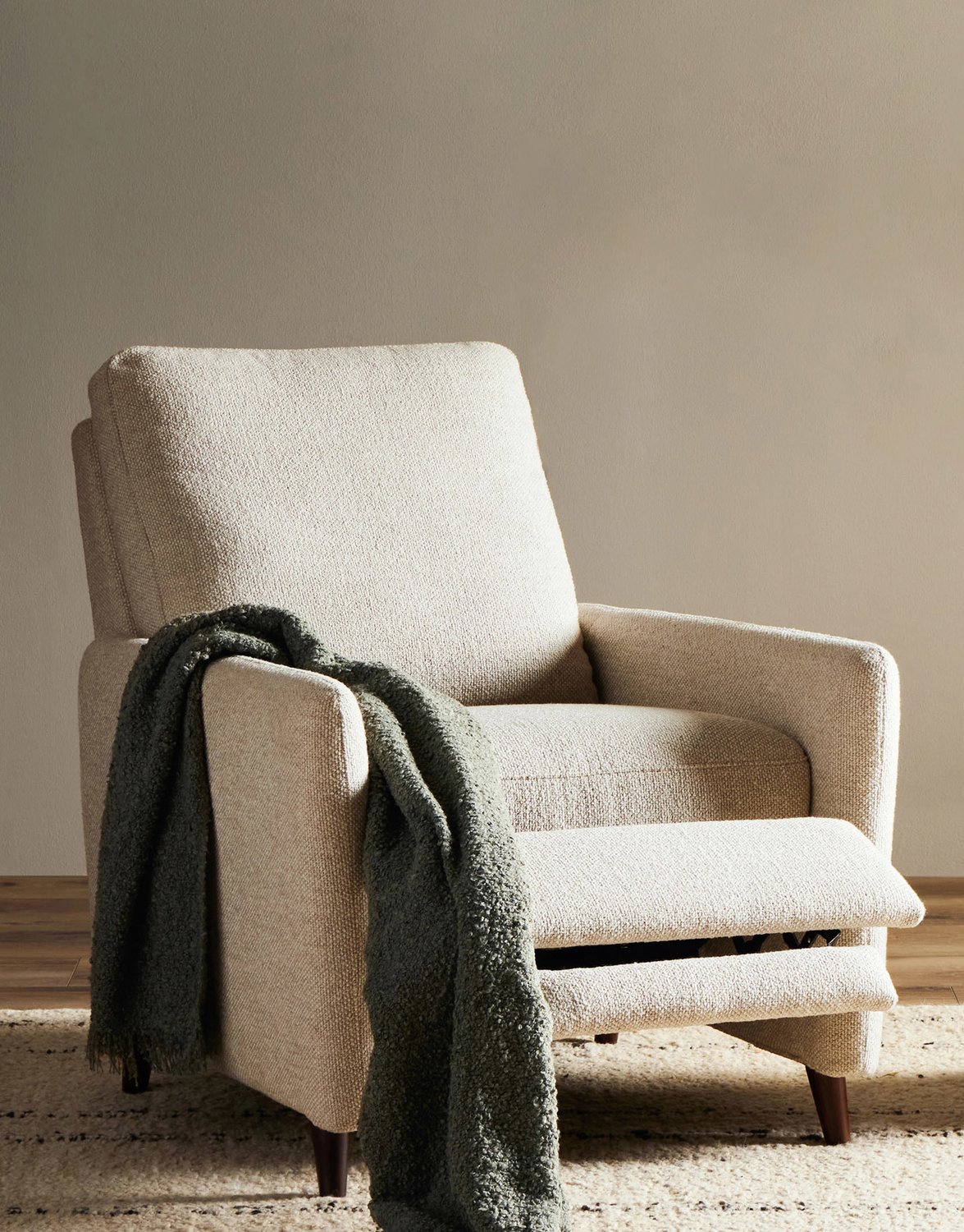Beige reclining accent chair with gray throw draped on top