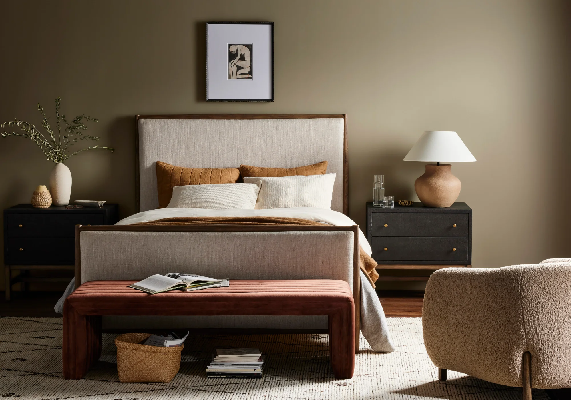 Bedroom showcasing a soothing neutral color palette. An upholstered headboard is accompanied by two matching black nightstands. A brown bench rests at the foot of the bed and a beige rug ties the space together.