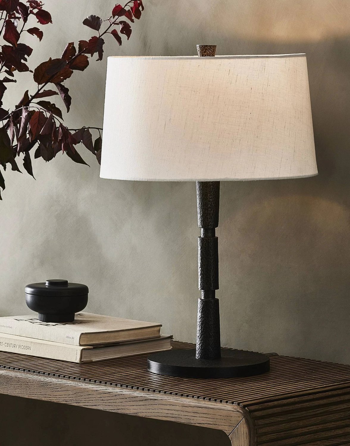A lamp on a wooden table next to a plant.