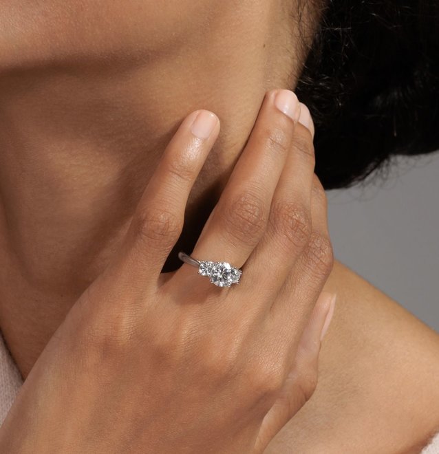 A woman wearing a 3 stone diamond engagement ring