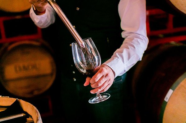 A winemaker tests wine from a barrel