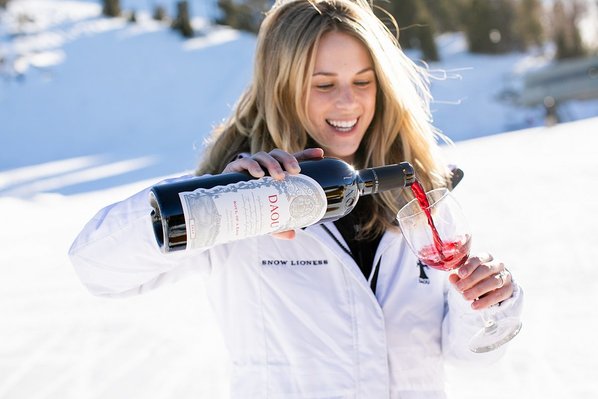 A woman in a DAOU jacket pours a glass of red wine